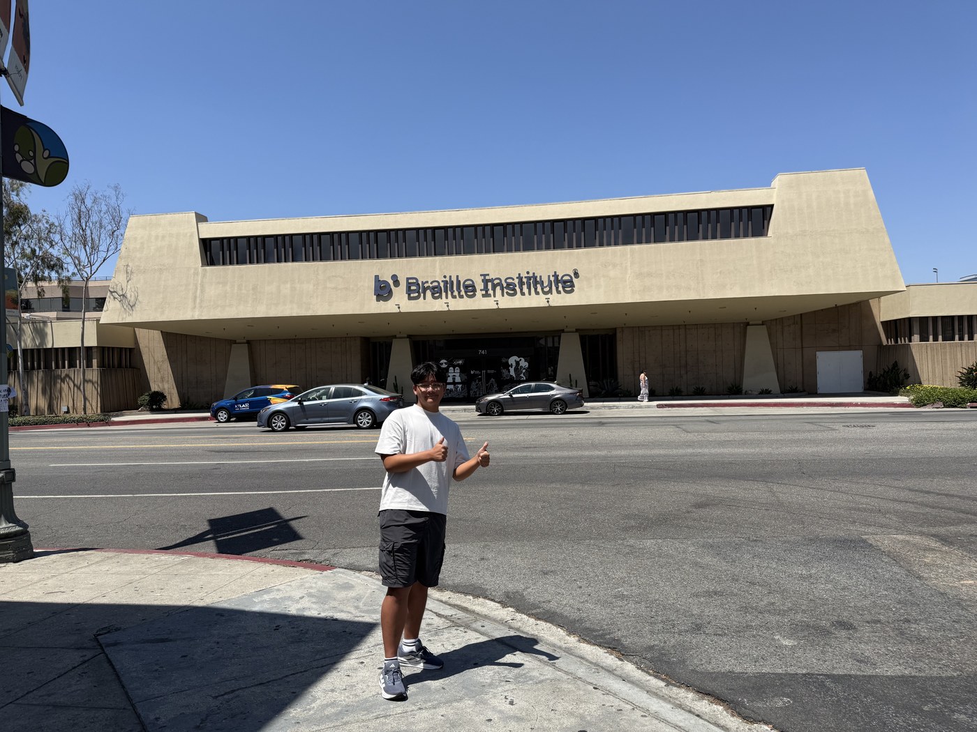 Ashton H. Jung giving a thumbs-up in front of the Braille Institute building in Los Angeles